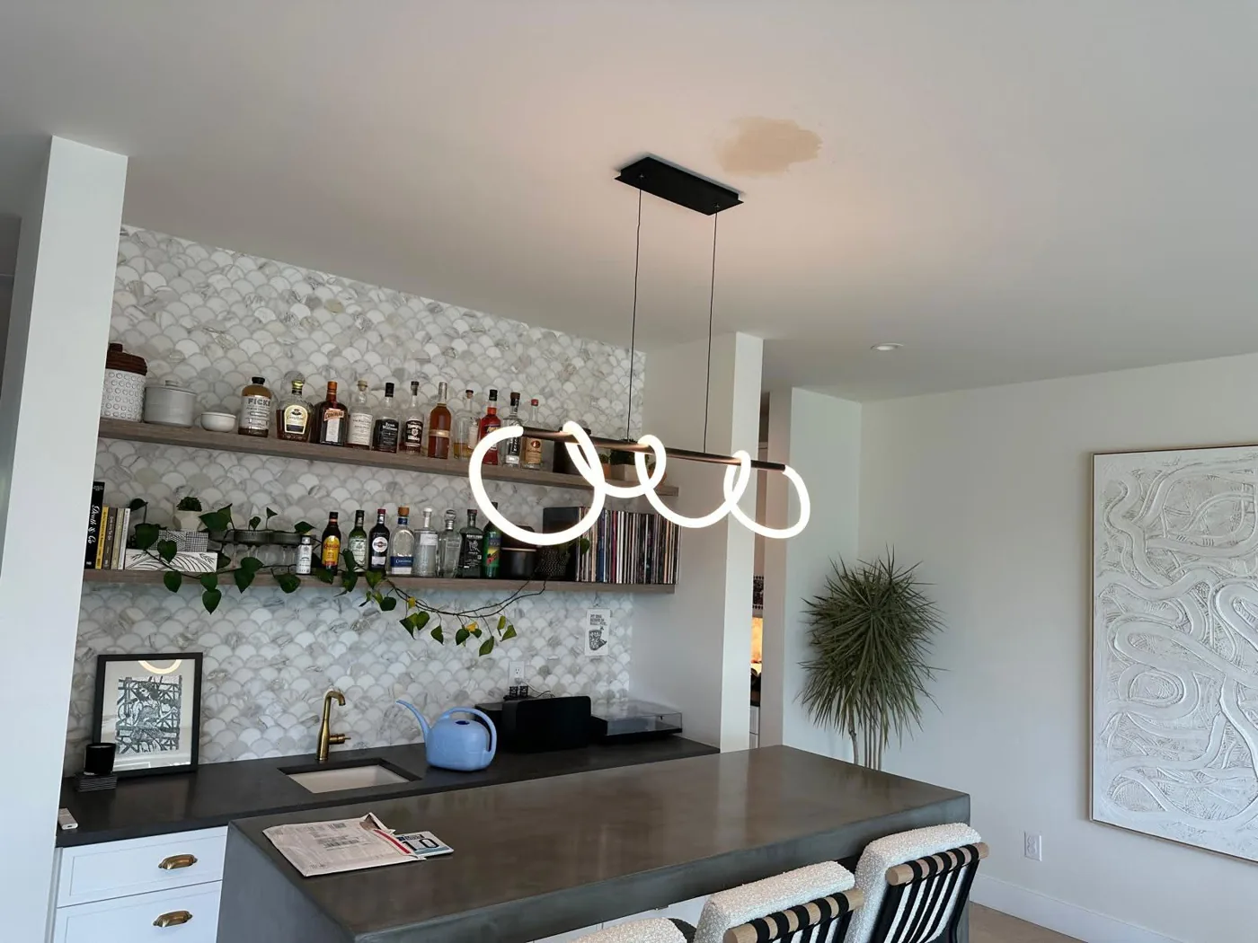 Looped LED pendant light installed over a home bar
