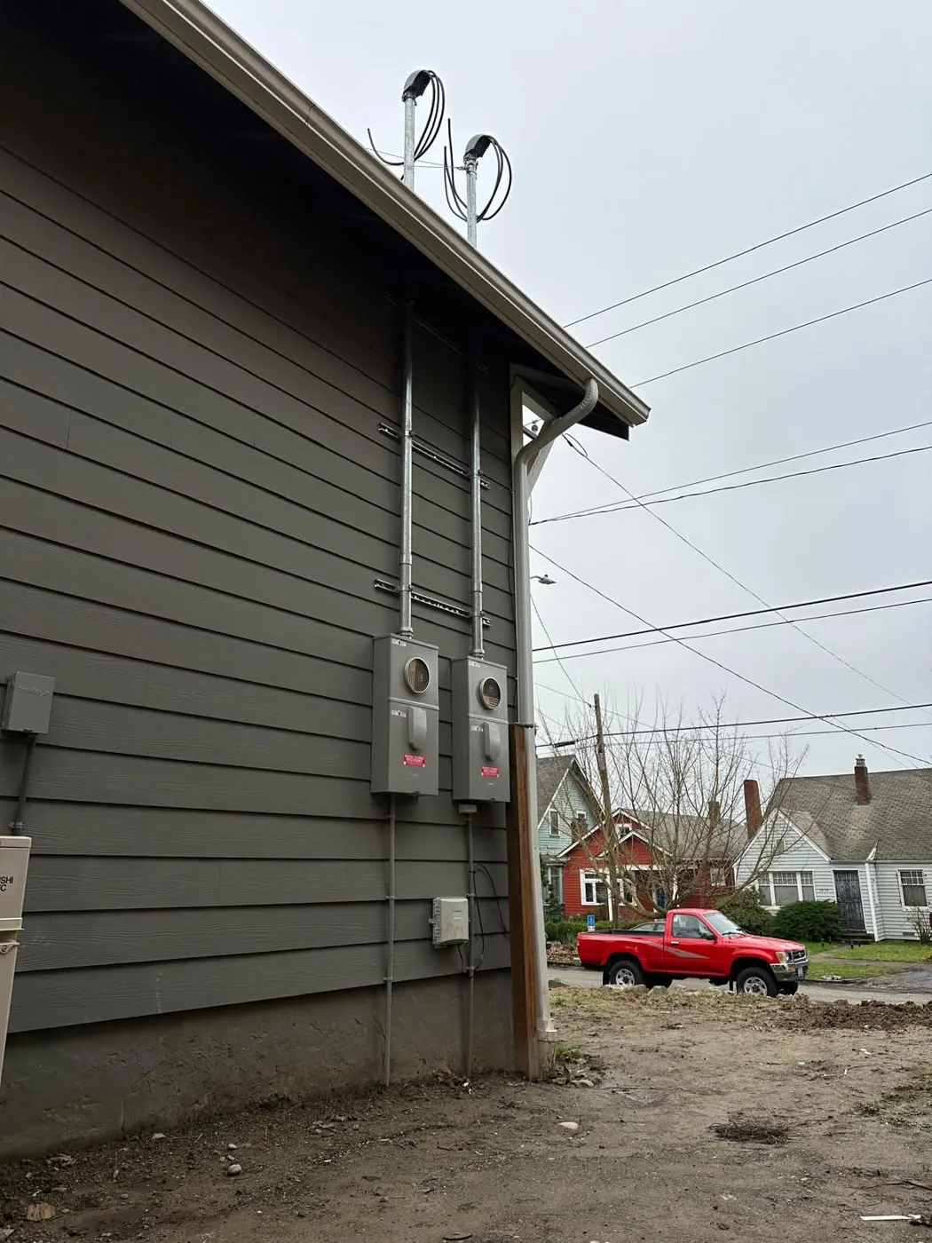 Two new meter bases with service masts on the side of a house